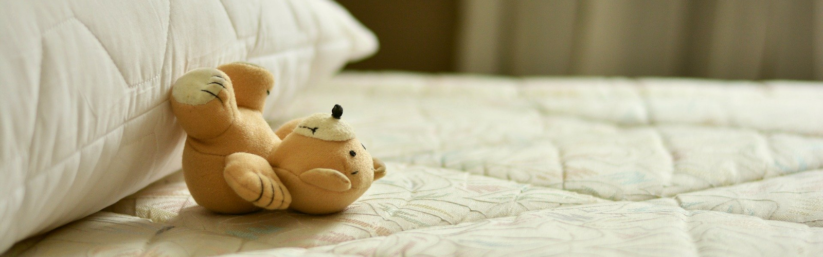 Teddy bear lying on bare mattress