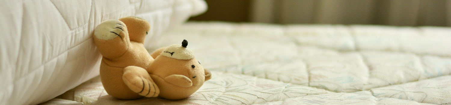 Teddy bear lying on bare mattress